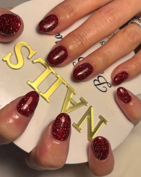 Rich ruby red glitter gel nails on an almond shape